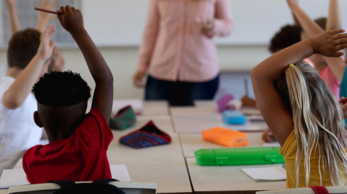 Classroom with students raising their hands. 